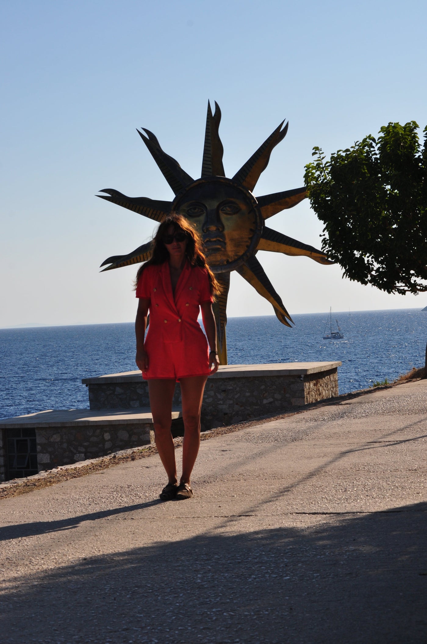 Eleanna Tabouri, Creative Director of Nevro Blazer, infant of the Jeff Koons installation Apollo Sun in Hydra wearing the Bloody Mary Nevro Blazer Terry playsuit