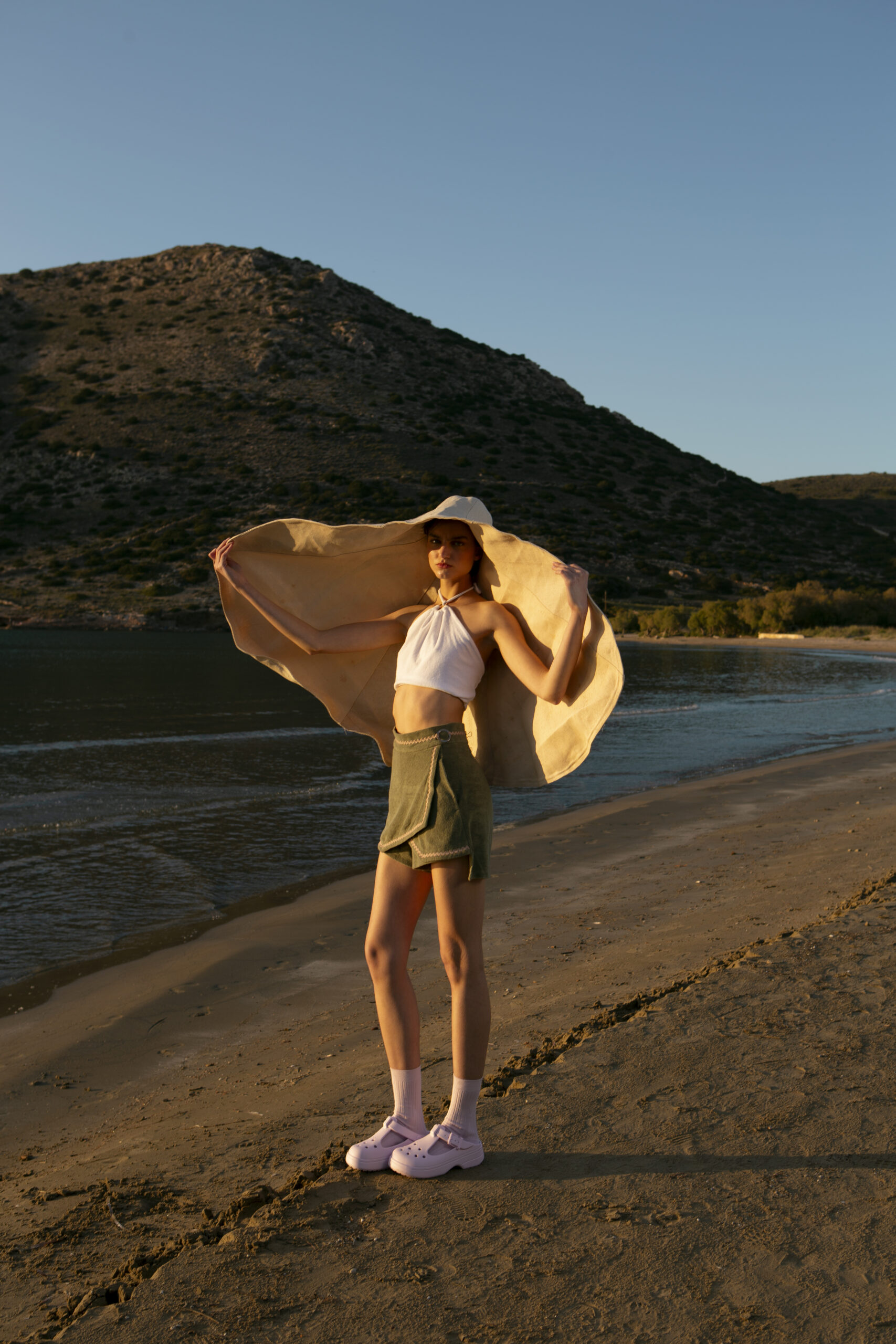 High-waisted terry cloth wrap shorts in olive green, trimmed with beige zig-zag piping and finished with engraved gold-tone hardware—crafted for sunlit days and sculptural silhouettes.