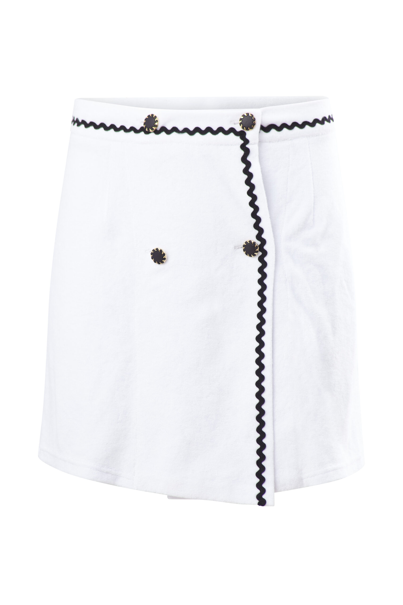 A sculptural take on summer tailoring, this white terry mini skirt features an asymmetrical front, black zig-zag trim, and sunburst buttons—echoing the bold contrast and purity of the Volax landscape.